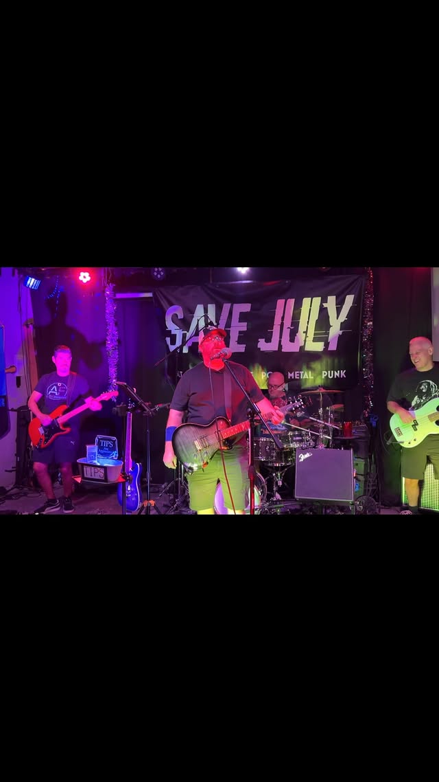 Singer at the mic mid-song with the full band behind him in purple light