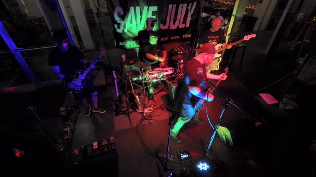 Overhead wide shot of the whole band playing under coloured stage lights