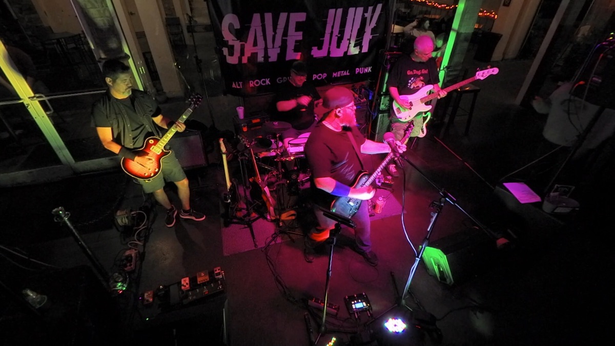 Save July on stage under pink and purple lights
